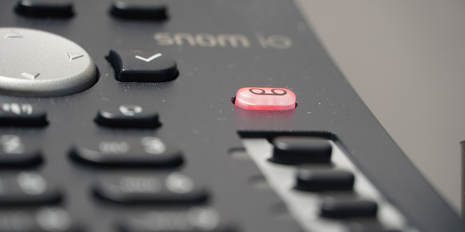 A black phone with an illuminated red voicemail button.